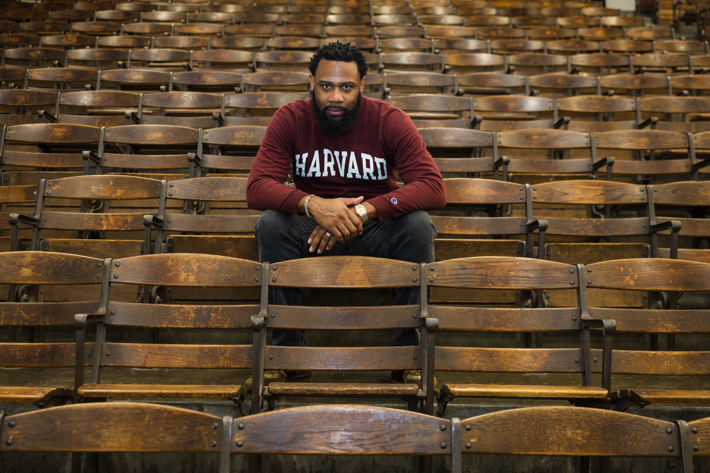 Rodriquez Wright II seated alone in a lecture hall of wooden seats