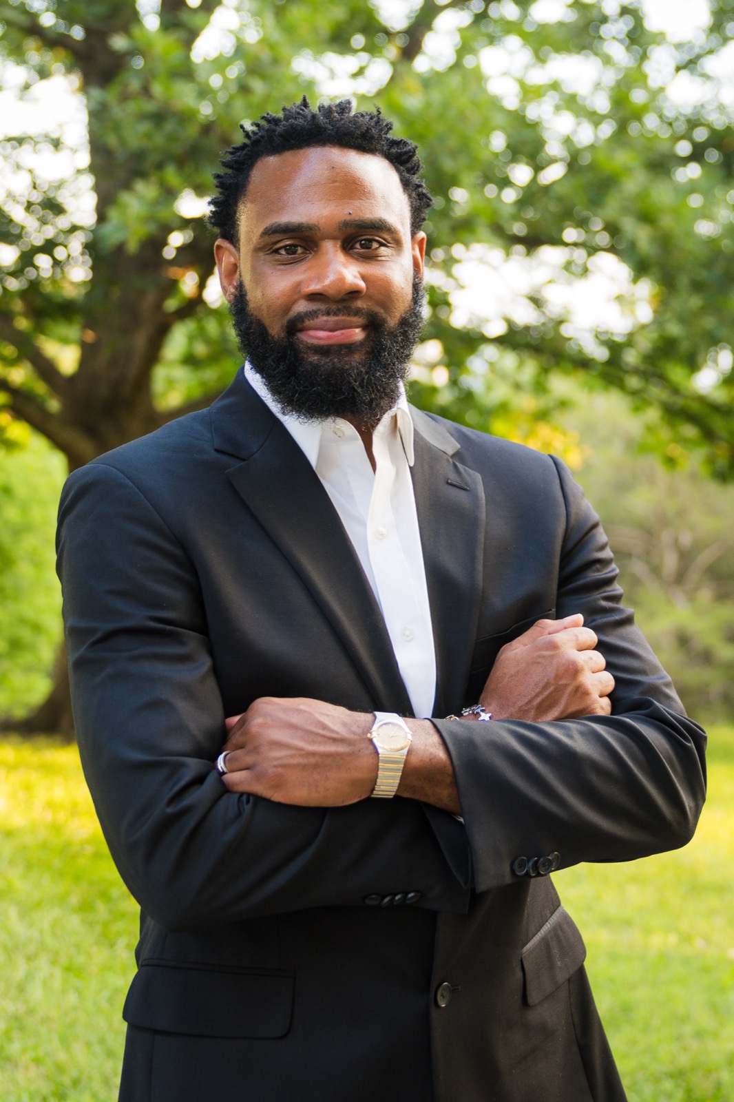 Rodriquez Wright II outdoors in a black suit, arms crossed